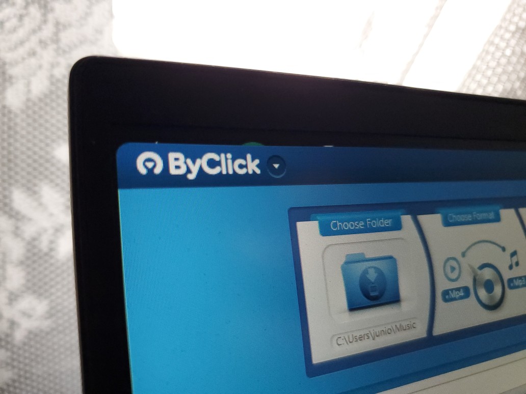 ByClick Downloader, el mejor descargador de videos de YouTube que se muestra en la pantalla de una computadora portátil con una cortina blanca detrás de la computadora